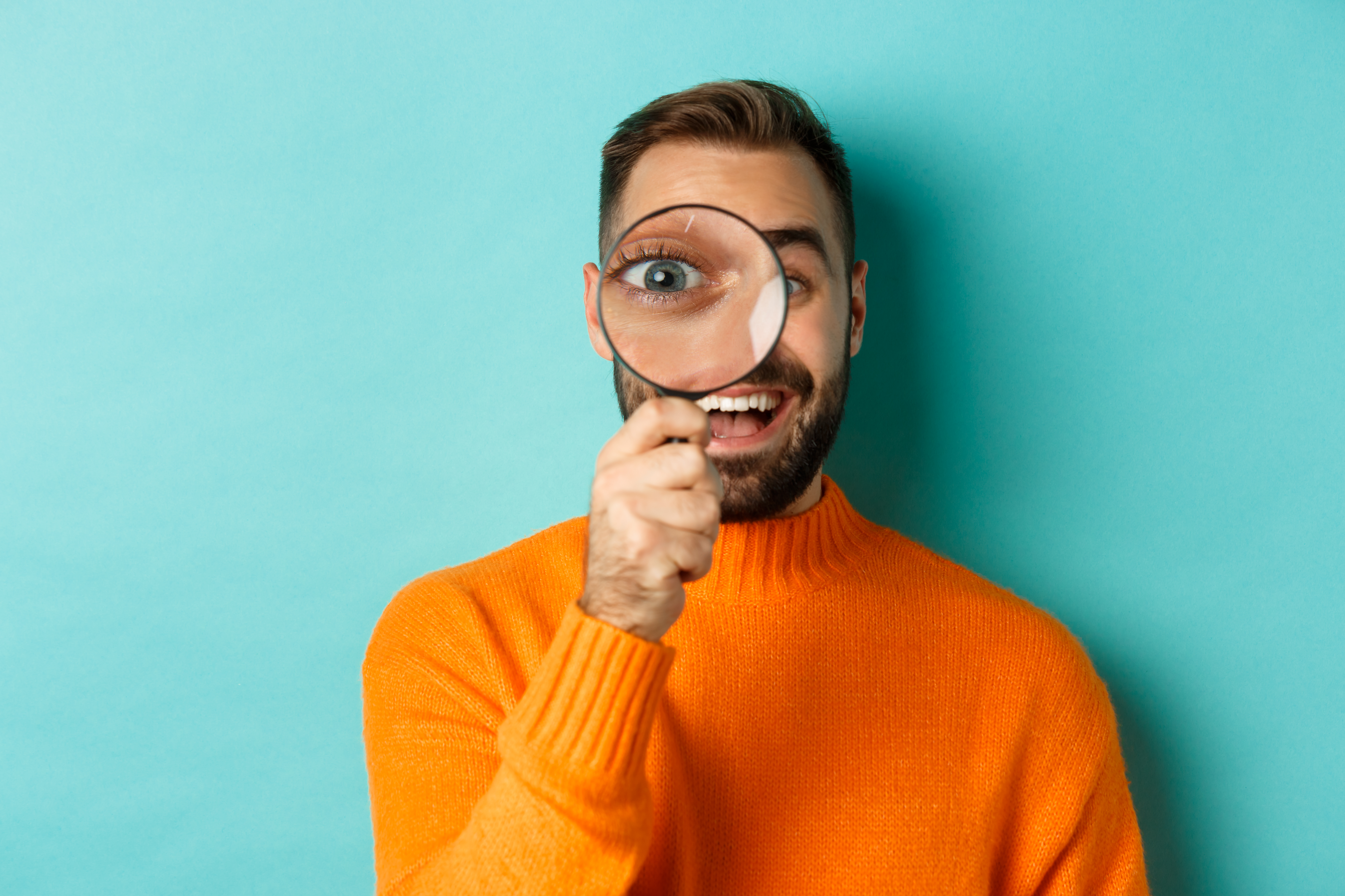 homme-drole-regardant-travers-loupe-recherche-enquete-quelque-chose-debout-dans-pull-orange.jpg